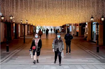  ?? — AFP ?? People wearing masks walk along Hanjie shopping street in Wuhan, China on Friday. Wuhan where Covid-19 first emerged last year, partly reopened on March 28 after more than two months of near total isolation.