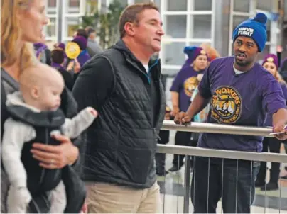  ?? Joe Amon, The Denver Post ?? Michael Ramey, right, tries to engage passengers exiting the terminal at DIA on Tuesday. Fast-food, home-care and janitorial workers launched their Denver Airport Campaign to fight for better wages.