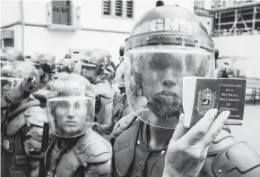  ?? EFE ?? Una mujer sostiene una Constituci­ón frente a un agente de la Guardia Nacional.