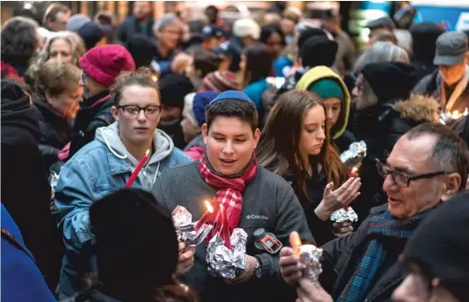  ?? MAX HERMAN/FOR THE SUN-TIMES ?? People light candles Sunday before a vigil in Chicago’s Federal Plaza in memory of victims of the Tree of Life synagogue mass shooting in Pittsburgh and other victims of violence.