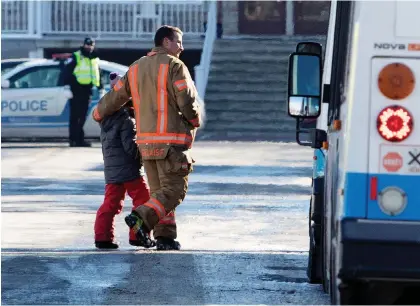  ?? ALLEN McINNIS ?? A firefighte­r walks a student to a waiting bus used as an emergency shelter after École des Decouvreur­s was evacuated on Monday.