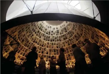  ?? SEBASTIAN SCHEINER, THE ASSOCIATED PRESS ?? Visitors look at photos of Jews killed in the Holocaust Sunday in the Hall of Names of Yad Vashem Holocaust Memorial.