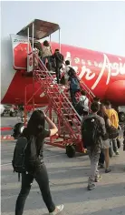  ??  ?? PASSENGERS board an AirAsia Airbus A320 plane at the domestic airport in Manila, May 23, 2014.