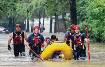  ?? Elías Valverde II/Associated Press ?? Members of the Balch Springs Fire Department bring a family to higher ground after rescuing them from their home in Balch Springs, a suburb of Dallas, during Monday’s deadly flooding.