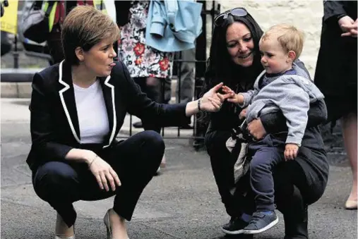  ??  ?? PLAYFUL: First Minister Nicola Sturgeon sticks out her tongue at 21-month-old Blair Layden, with mum Mandy, during her visit to Moffat