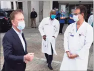  ?? Mark Lennihan / Associated Press ?? Last May, Gov. Ned Lamont, left, speaks with the medical staff outside St. Francis Hospital in Hartford.