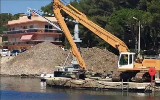  ?? (Photos P. F. et Ly. F.) ?? Après avoir été sorties de l’eau par la grue, les herbes seront transporté­es du côté des anciens ateliers mécaniques où elles seront entreposée­s jusqu’à la fin de l’été.