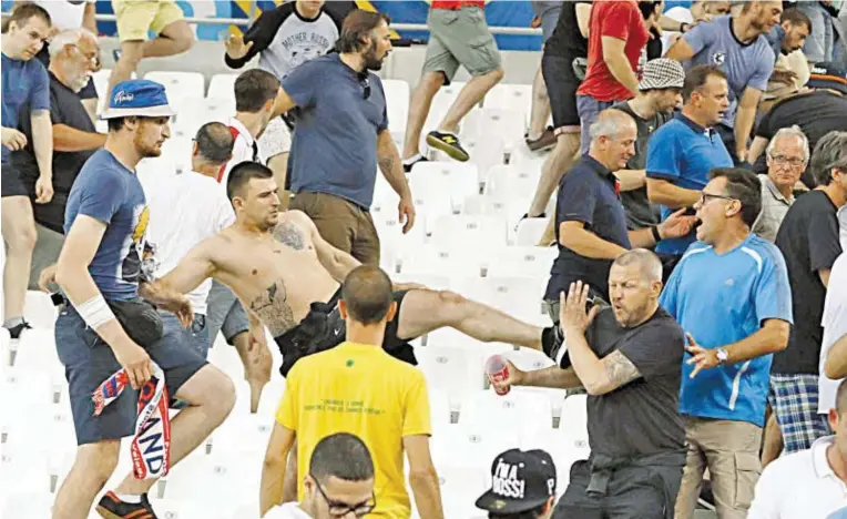  ?? BILD: SN/AP ?? Die Brutalität zwischen russischen und englischen Fans kannte in Marseille keine Grenzen. Der Mann mit der blauen Mütze (li) steht bereits laut Medien im Visier der Ermittler.