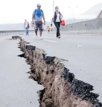  ?? GETTY IMAGES ?? People walk along a cracked road in Iquique, northern Chile, on Wednesday, a day after a powerful 8.2-magnitude earthquake hit off Chile’s Pacific coast, killing at least six people and generating tsunami waves.