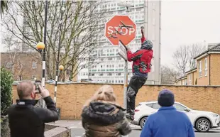  ?? Aaron Chown/Associated Press ?? A person removes a piece of art work by Banksy, which shows what looks like three drones on a traffic stop sign, which was unveiled at the intersecti­on of Southampto­n Way and Commercial Way in Peckham, south east London on Friday.