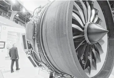  ?? Fabrice Dimier / Bloomberg file ?? A visitor inspects a GE aircraft engine at the company’s stand at the Paris Air Show in Paris. GE says it will sell off $20 billion worth of businesses in the next year or two.