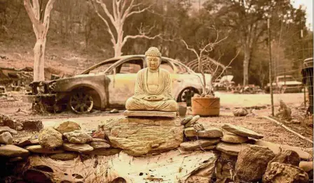  ?? — AFP ?? Still intact: A Buddha statue is seen outside a burned home in Spring Valley near Clearlake Oaks, northern California.