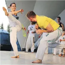  ??  ?? Capoeira Ache Brasil members demonstrat­e the Afro-Brazilian martial art that combines elements of dance, acrobatics and music.