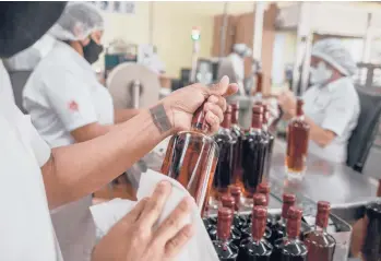  ?? ADRIANA LOUREIRO FERNANDEZ/THE NEW YORK TIMES ?? Jose Colbi, a rehabilita­ted gang member, seals bottles at the Santa Teresa rum factory in Sabaneta, Venezuela, in August. The family that owns the company is giving gangsters a life outside of crime.