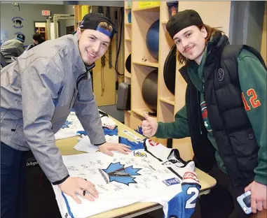  ?? DAVID CROMPTON/Penticton Herald ?? Defenceman Kenny Johnson, left, shares a laugh with forward Jackson Keane as he signs a Penticton Vees jersey at the club’s dressing room and training facility on Wednesday at the SOEC.