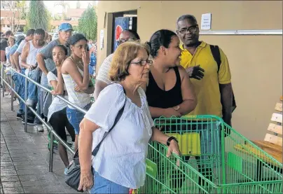  ?? AP PHOTO ?? People wait in line outside a grocery store to buy food that wouldn’t spoil and that they could prepare without electricit­y, in San Juan, Monday.