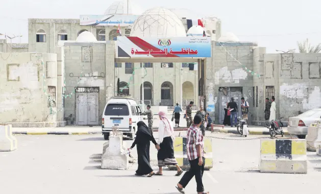  ??  ?? People walk past the municipali­ty’s headquarte­r of the Red Sea port city of Hodeida, Feb. 13, 2019.