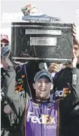  ?? TERRY RENNA / AP PHOTO ?? Denny Hamlin raises the trophy in Victory Lane after winning the NASCAR
Daytona 500 on Sunday.