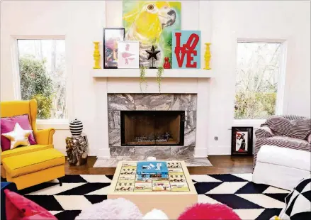  ?? TEXT BY SHANNON DOMINY. PHOTO BY REYNOLDS ROGERS. ?? The bold and colorful decor of Paola and Jeff Roder’s home is inspired by the Pop Art movement. Paola, who is a designer and interior stylist, drew from the era’s affinity for primary colors and daring patterns for the living room decor, including the bright yellow chair from Ikea and the parrot painting above the mantel by Natalie Flor Negron. Their coffee table is topped with hand-painted tiles from Israel, and it was passed down from Jeff’s mother.