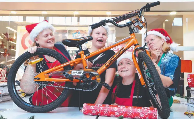  ?? Picture: GLENN HAMPSON ?? Volunteers Anna McEwan, Isabella Swindley, 12, Angel Hair, 16, and Colleen Sutton try to figure out how to wrap a bike at Robina Town Centre.