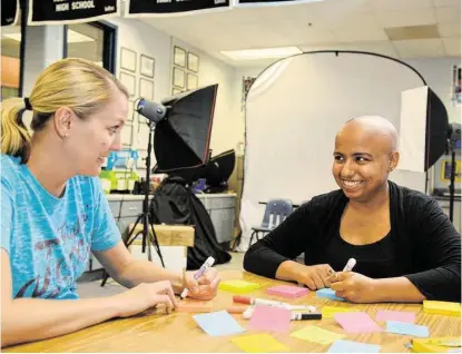  ?? Jerry Baker ?? Klein Collins journalism teacher and publicatio­ns adviser Allison Denman, left, joins senior Sanah Jivan, right, for a positive note-making session.