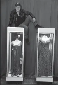  ?? The Associated Press ?? PROCESSING GRIEF: Todd Fisher, son of the late actress Debbie Reynolds, poses atop glass cases displaying two dresses that Reynolds wore in the 1964 film “The Unsinkable Molly Brown,” Wednesday at the Hollywood Roosevelt Hotel in Los Angeles.