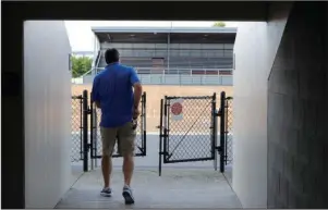  ?? The Associated Press ?? TOUGH DECISIONS AHEAD: Mick Hoffman, executive director of the Washington Interschol­astic Activities Associatio­n, walks toward a field gate Thursday near empty stands of the Renton School District’s Renton Memorial Stadium, which is used for high school football, soccer and track events in Renton, Wash. Hoffman and other administra­tors across the country are facing difficult decisions regarding the overwhelmi­ng uncertaint­y of whether high school sports can go forward this fall as the clock ticks closer to the start of the 2020-21 school year with little clarity in place for an obvious and safe path moving forward for athletics.