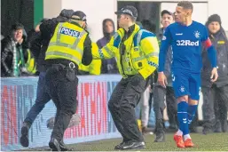  ??  ?? James Tavernier looks on as the fan is led away by police.