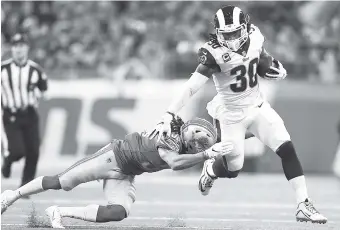  ?? AP PHOTO/REY DEL RIO ?? Los Angeles Rams running back Todd Gurley pulls away from Lions defensive back Mike Ford during last Sunday’s game in Detroit. Gurley finds himself in exclusive company. He has gained 1,649 yards from scrimmage and scored 19 TDs so far this season. Only six players have topped those marks in the first 12 games.