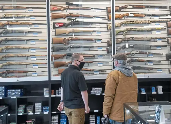  ?? Emily Matthews/Post-Gazette ?? An employee at Allegheny Arms and Gun Works and a customer talk in front of a case of long arms on Saturday in Bethel Park.