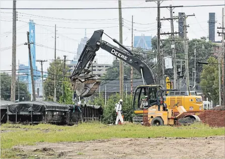  ?? MAX ORTIZ, DETROIT NEWS THE ASSOCIATED PRESS ?? Workers clear the land this week along West Jefferson Avenue and Schroeder Street in the Delray neighbourh­ood in Detroit. The land will be used for a truck and customs plaza for the Gordie Howe Internatio­nal Bridge between Detroit and Windsor.