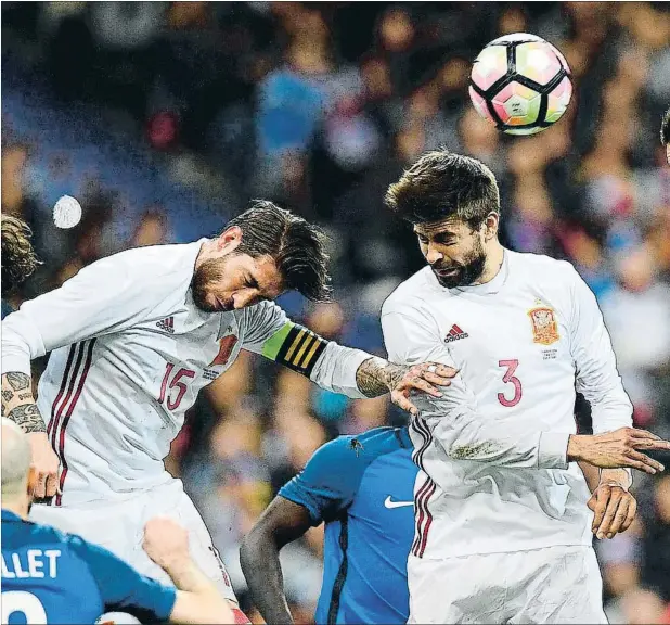  ??  ?? Sergio Ramos y Gerard Piqué, con la equipación blanca de la selección, saltando a por un balón, el pasado martes en el Stade de France