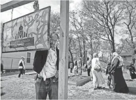  ??  ?? Omar Abdi fixes the sign at a community garden a block away from the Midtown Mosque on Jackson. JIM WEBER/ FILE / THE COMMERCIAL APPEAL