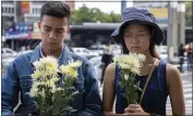  ?? GEMUNU AMARASINGH­E — THE ASSOCIATED PRESS ?? A couple offers flowers at the scene of a deadly mass shooting in Nakhon Ratchasima, Thailand.