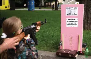  ?? The Associated Press ?? Victoria, 7, uses a plastic Kalashniko­v rifle to shoot balls at a portrait of Russian President Vladimir Putin at a street attraction in the centre of Lviv, Ukraine, on Saturday. The banner reads in Ukrainian: It’s not a shame to miss. It’s a shame not to try to shoot! Glory to Ukraine, Death to our enemies!