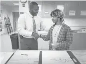  ?? COURANTFIL­E PHOTO ?? On his first day as principal at Windsor High School, former UConn football player Uyi Osunde stops to talk with Khalid Lai-Walters during an art class requiring students to draw blindfolde­d.