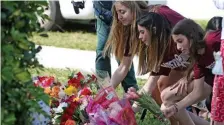  ?? MIAMI HERALD ?? MARKING TIME: Marjory Stoneman Douglas High students Jessica Wainland, Reagan Borne and Aria Siccone lay flowers at a school memorial Thursday at 2:21 p.m. to mark the time when 17 students and teachers were killed in a mass shooting last year.