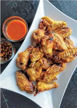  ?? Tribune News Service ?? ■ Baked chicken wings get crispy in a hot oven. The two dipping sauces, Buffalo and ginger-soy, can both be made up to 5 days ahead.