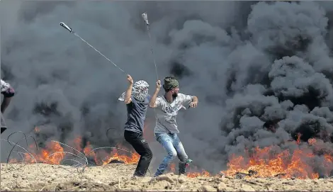  ?? AP PHOTO ?? In this April 27, 2018, photo, Palestinia­n protesters hurl stones at Israeli troops during a protest at the Gaza Strip’s border with Israel. President Donald Trump’s assertion that stones thrown by Latin American protesters at American troops should be treated as “rifles” has sparked debate about the appropriat­e response to rock throwing crowds — particular­ly after Nigerian troops appeared to use his comments as justificat­ion for a deadly crackdown on demonstrat­ors over the weekend. From the Gaza Strip to Africa to Europe, security forces have long dealt with stone throwers, albeit in very different ways.