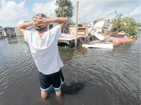  ??  ?? WHAT’S NEXT?: Larry Dimas walks around his destroyed trailer in Immokalee. Irma badly damaged his mobile home and destroyed another he used for rental income.