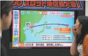  ?? Kazuhiro Nogi / AFP / Getty Images ?? A pedestrian look at a TV news report in Tokyo on a North Korean missile test that passed over Japan.