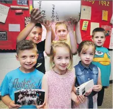  ?? DAN JANISSE ?? St. Rose elementary school students Aiden Samrah, left, Evan Samrah, Aubrey Langley, Parker Langley, Emerson Langley and Griffin Langley pose Monday with photos from a school time capsule.