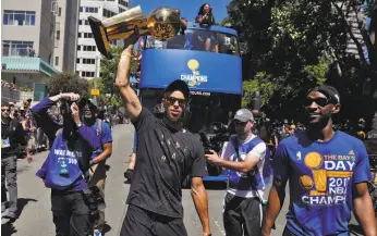  ?? Carlos Avila Gonzalez / The Chronicle ?? Stephen Curry (center) and Ian Clark celebrate the Golden State Warriors’ NBA championsh­ip during their parade through downtown Oakland.