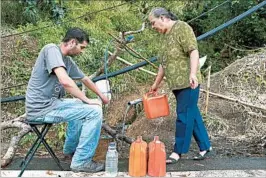  ?? MARIO TAMA/GETTY ?? A woman and her son collect spring water in Puerto Rico. After Hurricane Maria, one-third of the island lacks clean running water and about 85 percent of residents lack electricit­y.