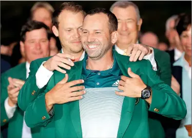  ?? AP/DAVID J. PHILLIP ?? Danny Willett (left) helps Sergio Garcia slip on his green jacket after Garcia outlasted Justin Rose in a sudden-death playoff to win the Masters on Sunday at Augusta National Golf Club in Augusta, Ga. Garcia birdied from 12 feet on the extra hole to capture his first major and become the third Spaniard, and first since Jose Maria Olazabal in 1999, to win the tournament.