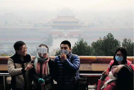  ?? ANDY WONG/THE ASSOCIATED PRESS ?? Visitors, some wearing masks to protect themselves from pollutants, share a light moment as they take a selfie Monday in Beijing.