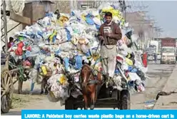  ?? —AFP ?? LAHORE: A Pakistani boy carries waste plastic bags on a horse-driven cart in Lahore.