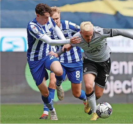  ?? Picture: Paul Greenwood/Getty ?? Rovers’ Luke Thomas tries to hold off a challenge from Wigan’s Luke Chambers