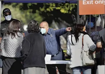  ?? Photog r aphs by Christina House Los Angeles Times ?? LOS ANGELES FIRE DEPARTMENT off icials checked credential­s Tuesday at a COVID- 19 vaccinatio­n site at the Crenshaw Christian Center in South L. A. The shots were meant exclusivel­y for healthcare workers.