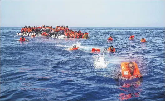  ?? AP PHOTO ?? African migrants try to reach a rescue boat from the Spanish aid organizati­on Proactiva Open Arms, after falling from a punctured rubber boat in the Mediterran­ean Sea, about 12 miles north of Sabratha, Libya, on July 23, 2017.